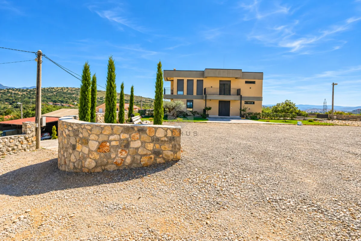 View of the courtyard and exterior of a modern two-story house.
