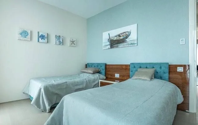 Furnished bedroom with two single beds and blue wall accents.