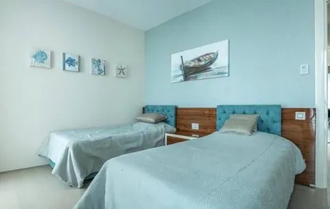Furnished bedroom with two single beds and blue wall accents. - image 6