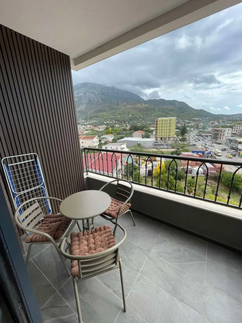 Furnished terrace with a table, chairs, and a view of the city and mountains.