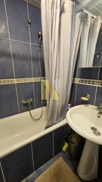 Manje kupatilo sa kadom, umivaonikom i plavim zidnim pločicama. - image 3