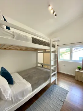 Bright bedroom with a white bunk bed and wooden flooring. - image 13