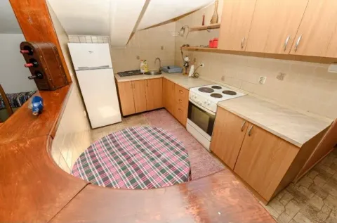 Small kitchen with wooden cabinets, stove, and a dining table. - image 4