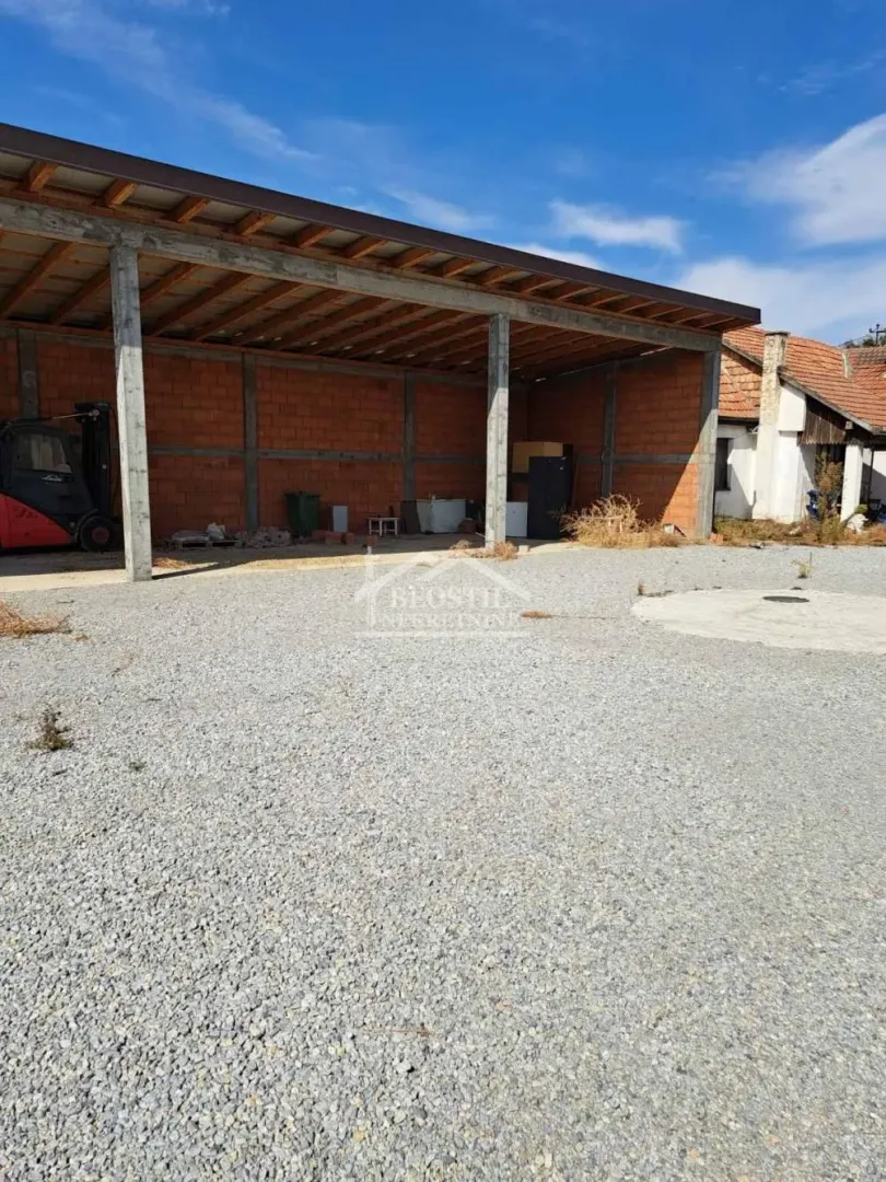 Pogled na natkriveni pomoćni objekat i dvorište posuto šljunkom.
