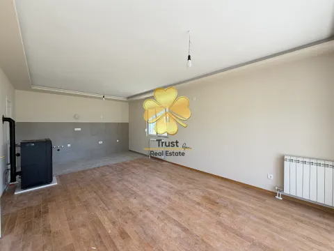 Empty living room with wooden flooring, tiled wall section, and a solid fuel stove. - image 3