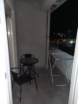 A balcony featuring a small table, two chairs, and a clothes drying rack at night. - image 10