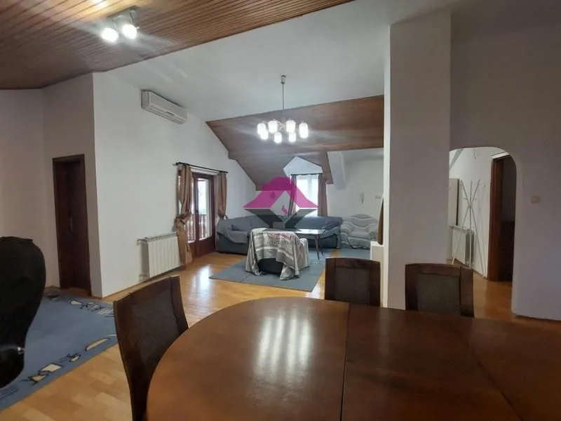 Prostrani dnevni boravak sa trpezarijom i drvenim plafonom.
