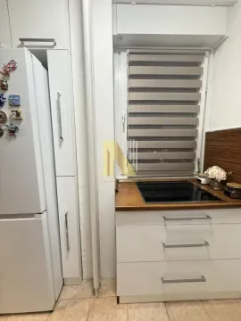 Deo kuhinje sa belim elementima, ugradnom pločom i frižiderom. - image 9
