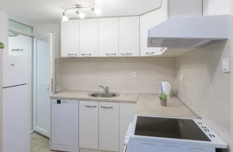 Small white kitchen with cabinetry and built-in appliances. - image 12