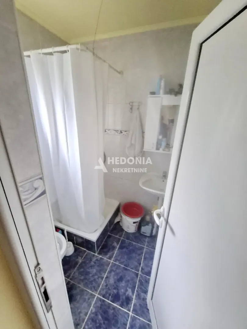 Manje kupatilo sa tuš kabinom i plavim podnim pločicama.
