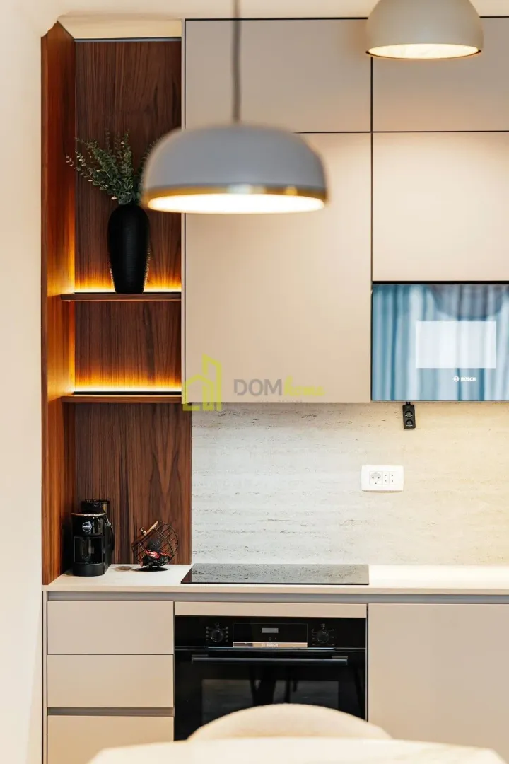 Modern kitchen with built-in appliances and illuminated wooden shelving.