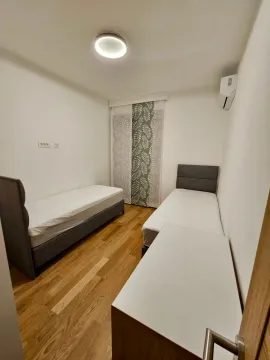 Spavaća soba sa dva singl kreveta i drvenim podom. - image 9