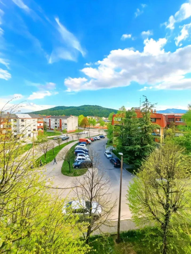 Pogled sa terase na naselje, parking i zelene površine.