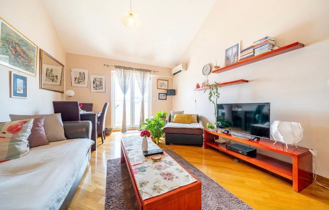 Furnished living room with a sofa, TV unit, and dining area.