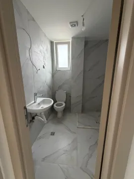 View of a bathroom with white marble-effect tiles, sink, and toilet. - image 6