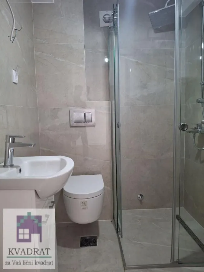 Modernly equipped bathroom with a shower cabin, washbasin, and toilet.