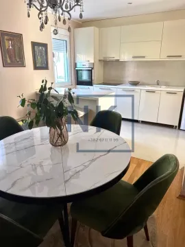 Kitchen with dining area equipped with white cabinetry and a round table with green chairs. - image 4