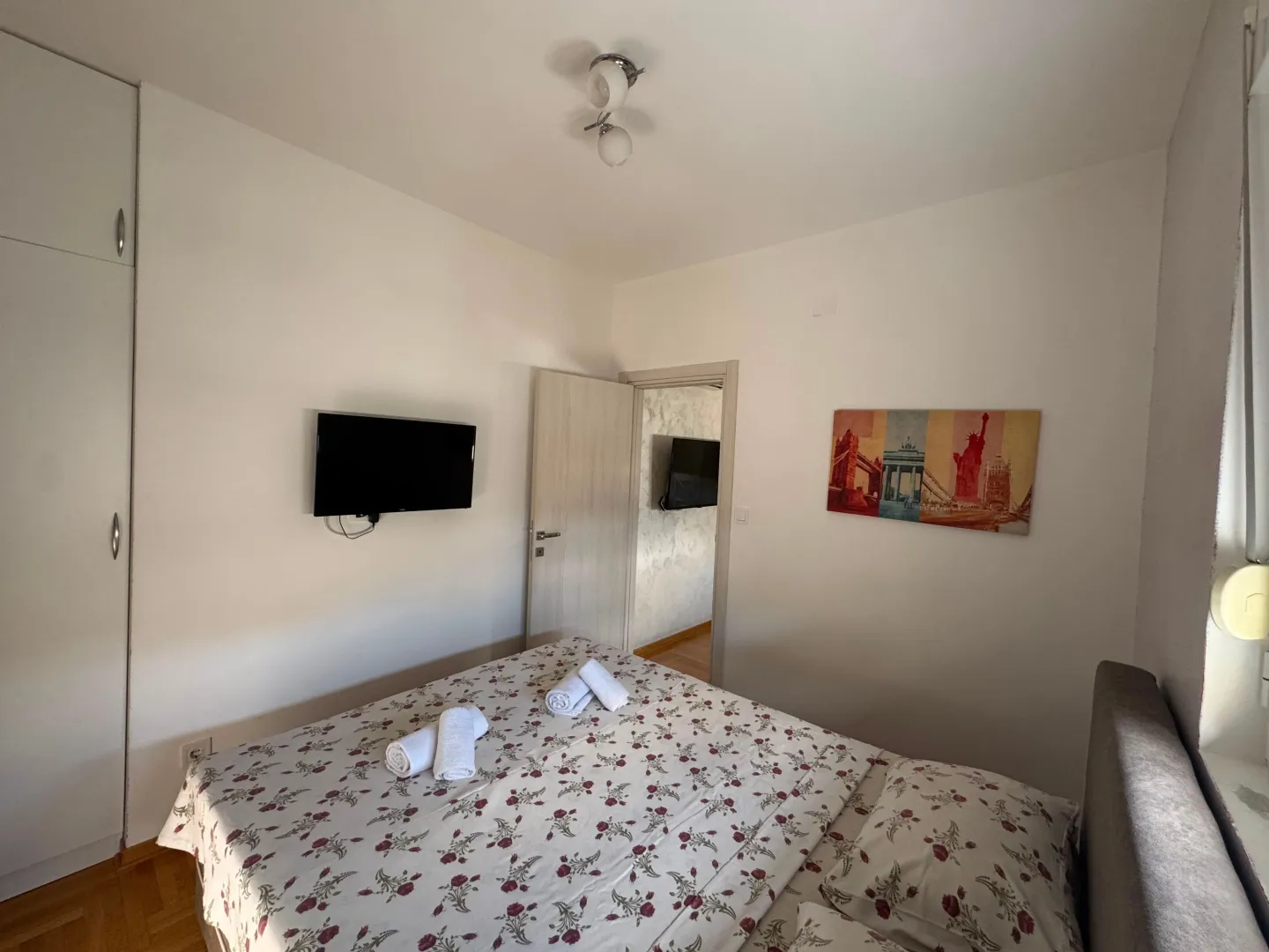 Bright bedroom with a double bed and a wall-mounted TV.