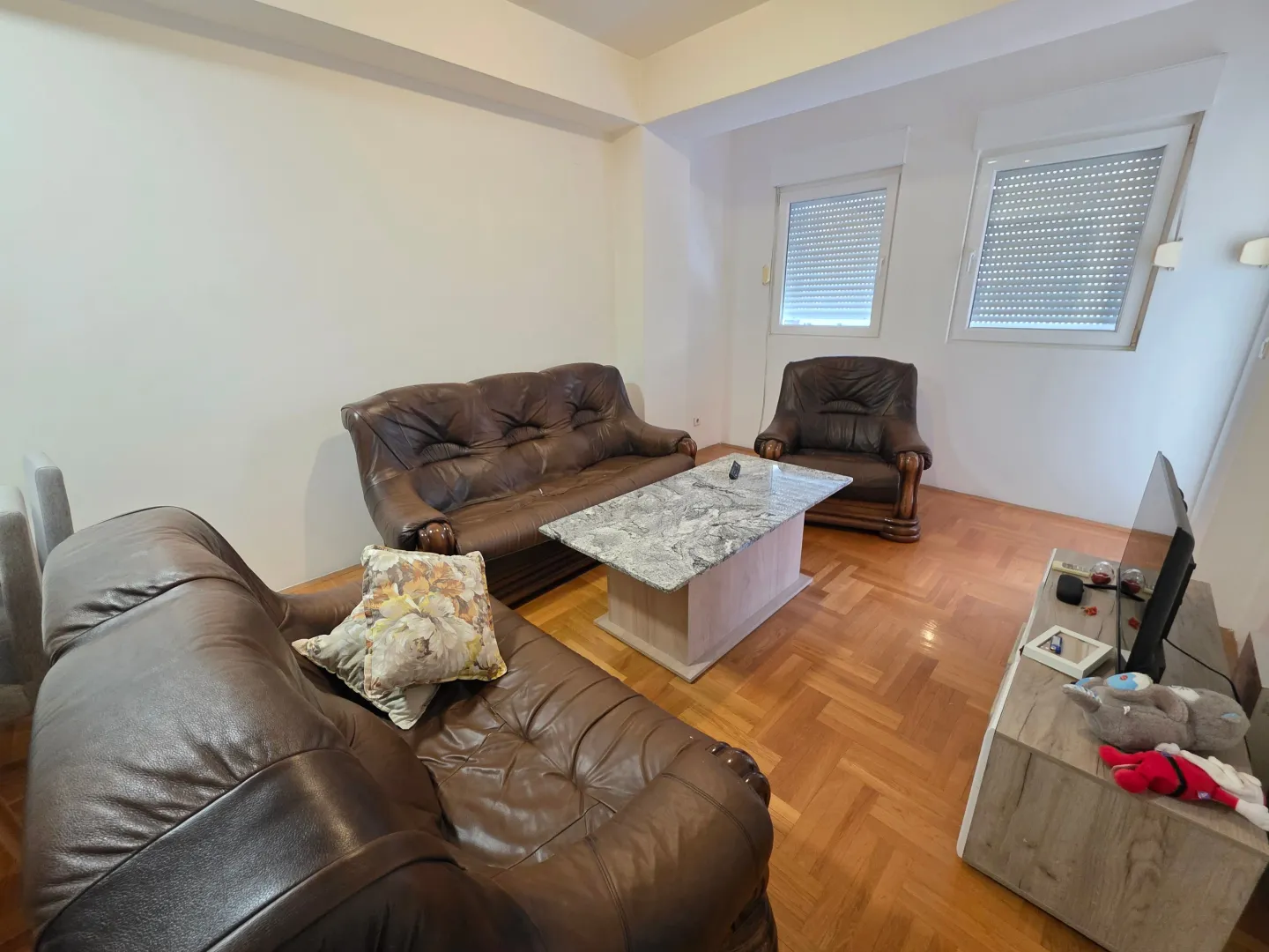 Living room with dark leather furniture and wooden flooring.