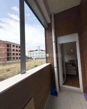 Natkriveni balkon sa pogledom na okolne zgrade i otvoren prostor. - image 7