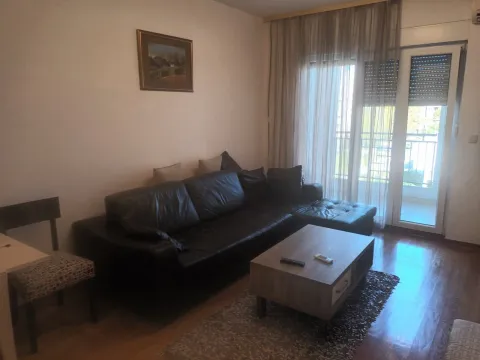 Dnevna soba sa crnom kožnom ugaonom garniturom, drvenim klub stolom i izlazom na terasu. - image 2