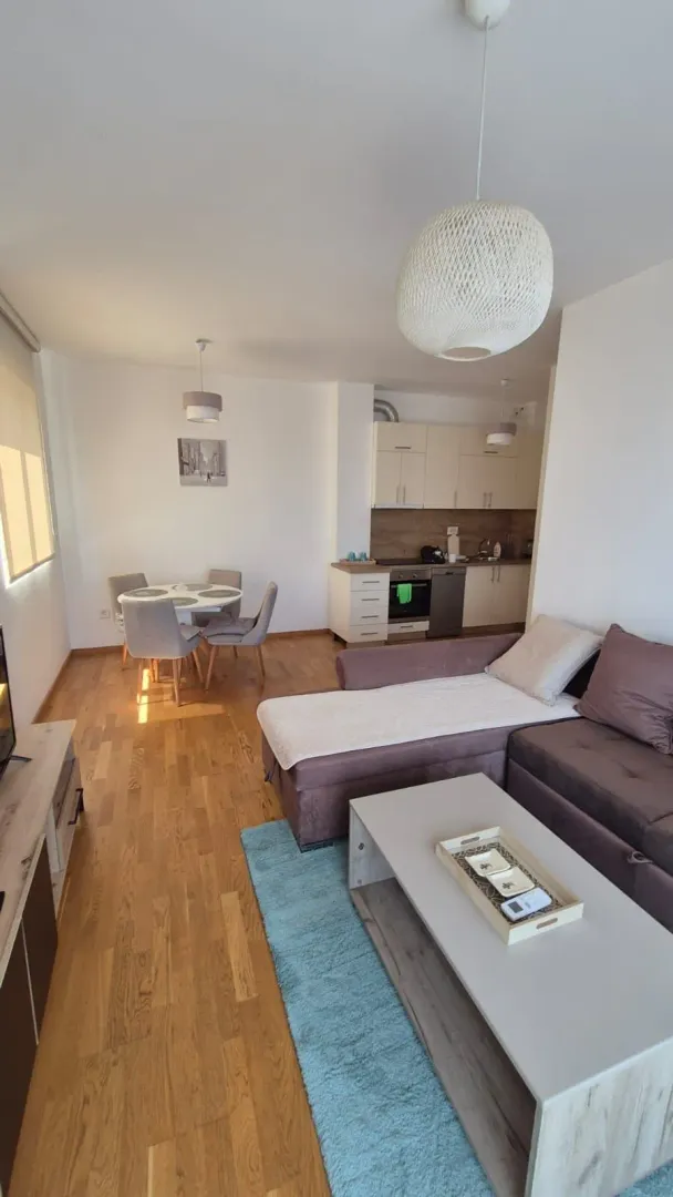 Living room with sofa set, dining area, and kitchen in the background.