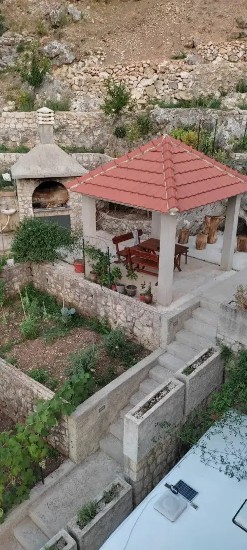 Terrace with a covered seating area, barbecue, and garden.