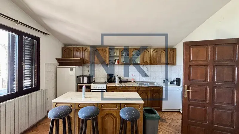 Kitchen with wooden cabinetry, an island, and bar stools.