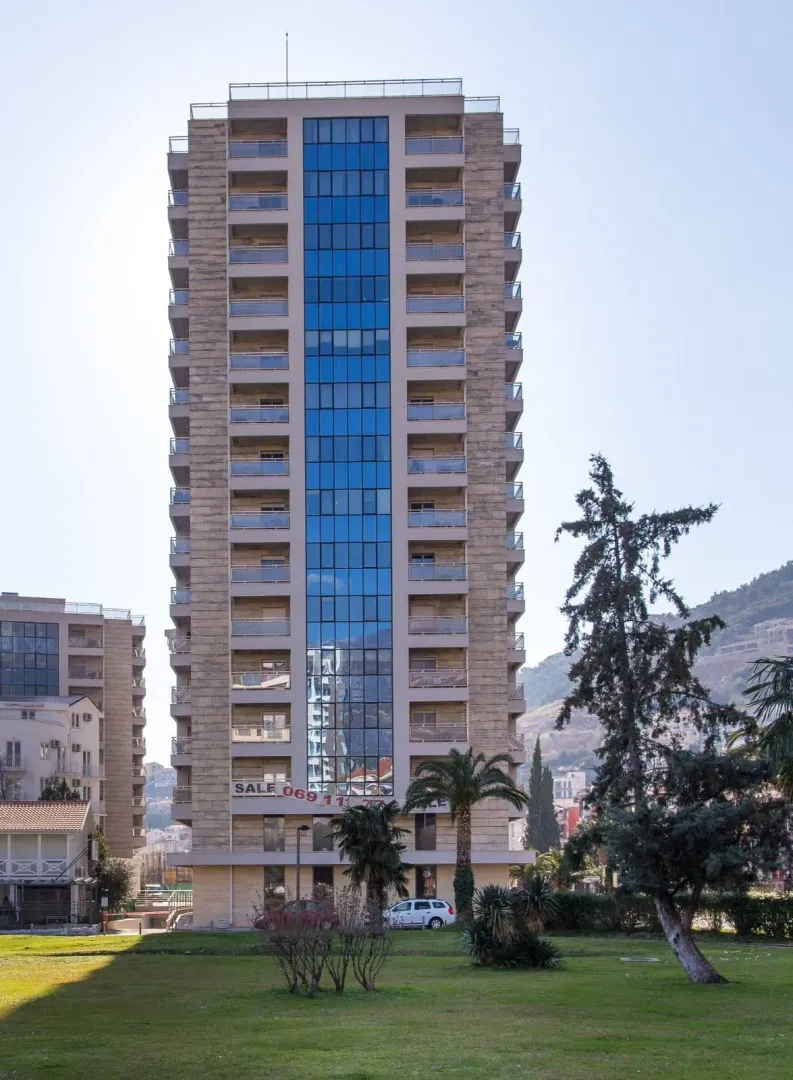 View of the front facade of a multi-story residential building with a landscaped yard.