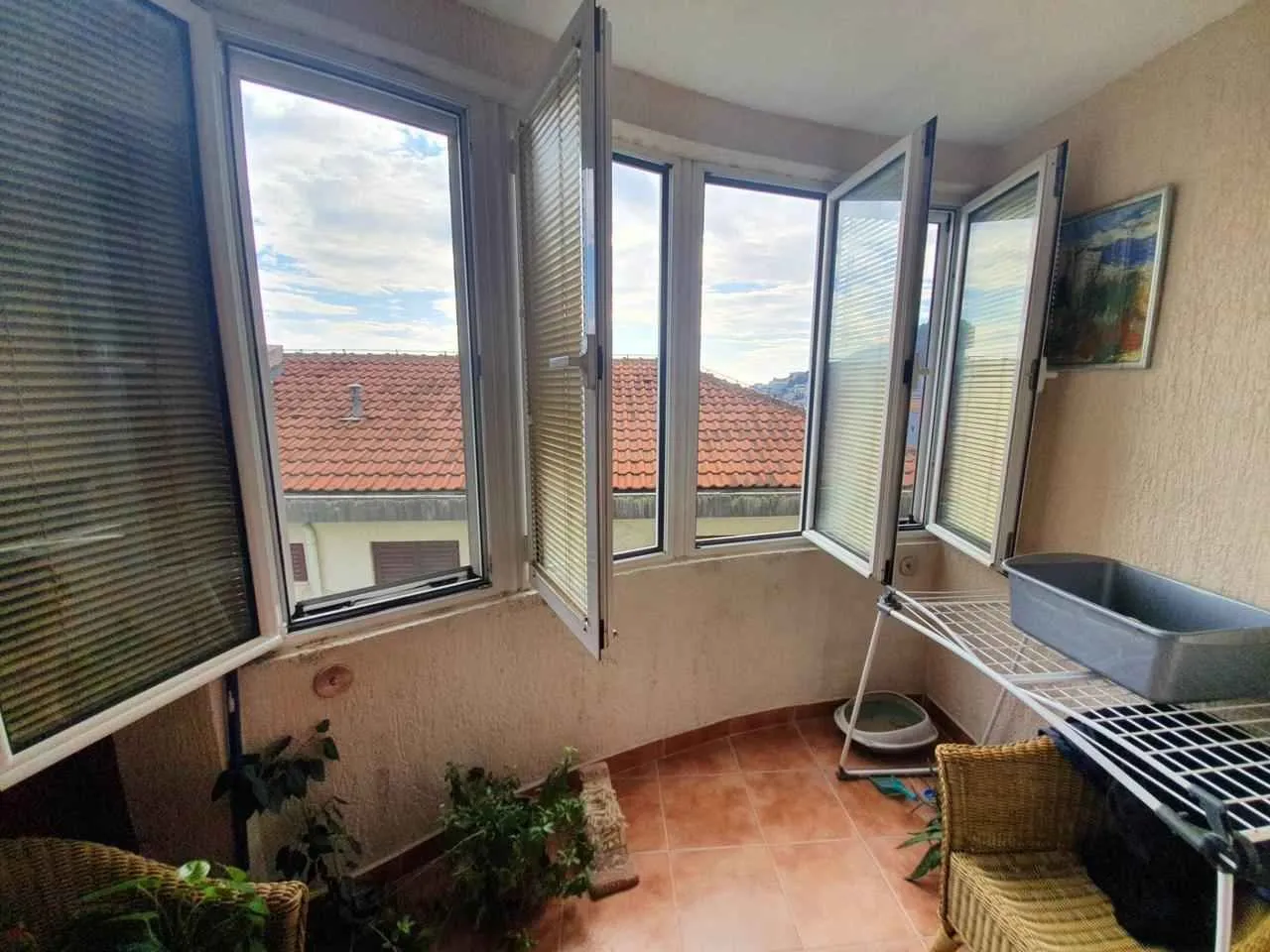Zastakljeni balkon sa prozorima i pogledom na okolne krovove.