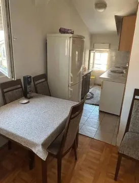 Trpezarija sa stolom i stolicama, i kuhinja u pozadini. - image 9