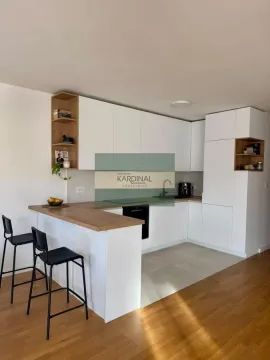 Moderna bela kuhinja sa šankom i drvenim detaljima. - image 4