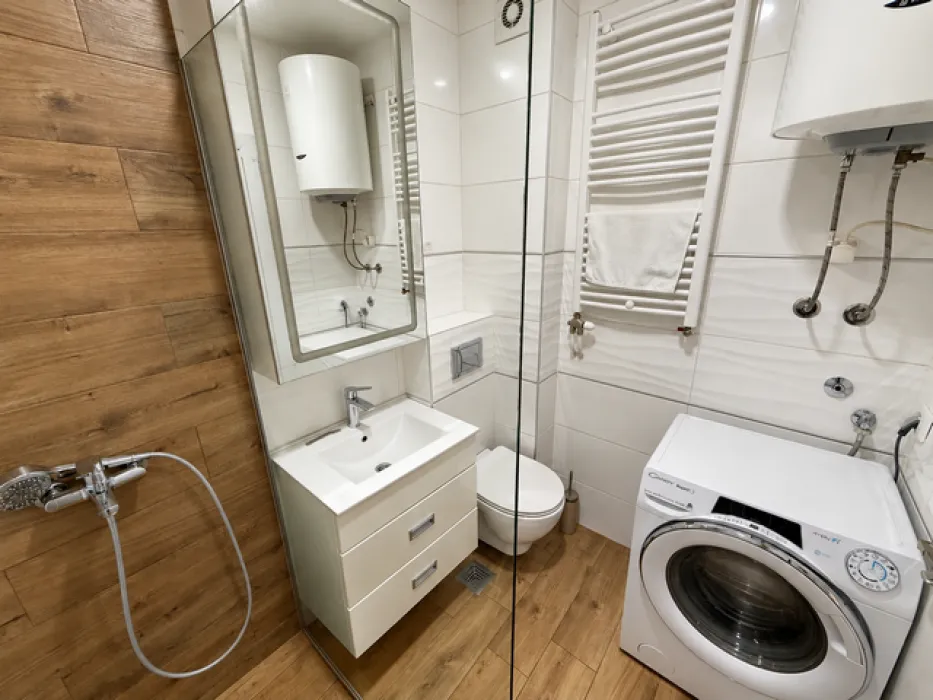 Bathroom with a shower cabin, washbasin, toilet, and washing machine.