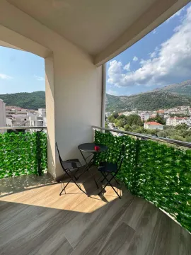 Furnished balcony with a table, chairs, and a nice view of the surroundings. - image 9