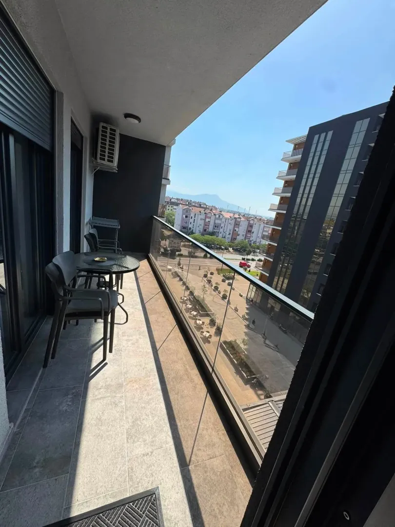 Spacious balcony with outdoor seating and a view of surrounding buildings and street.