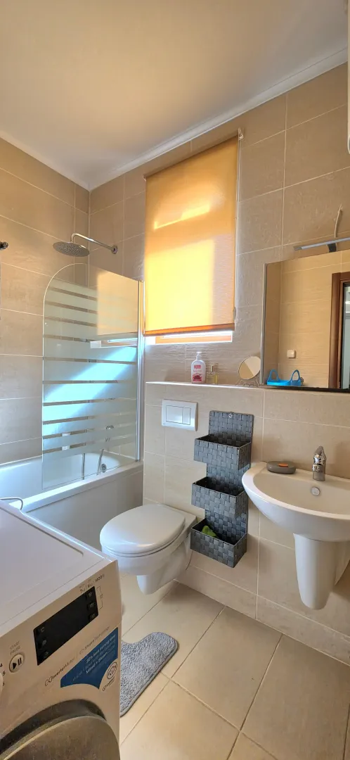 Fully equipped bathroom with a shower cabin, washbasin, and washing machine.