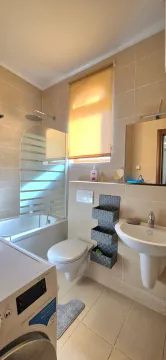 Fully equipped bathroom with a shower cabin, washbasin, and washing machine. - image 12