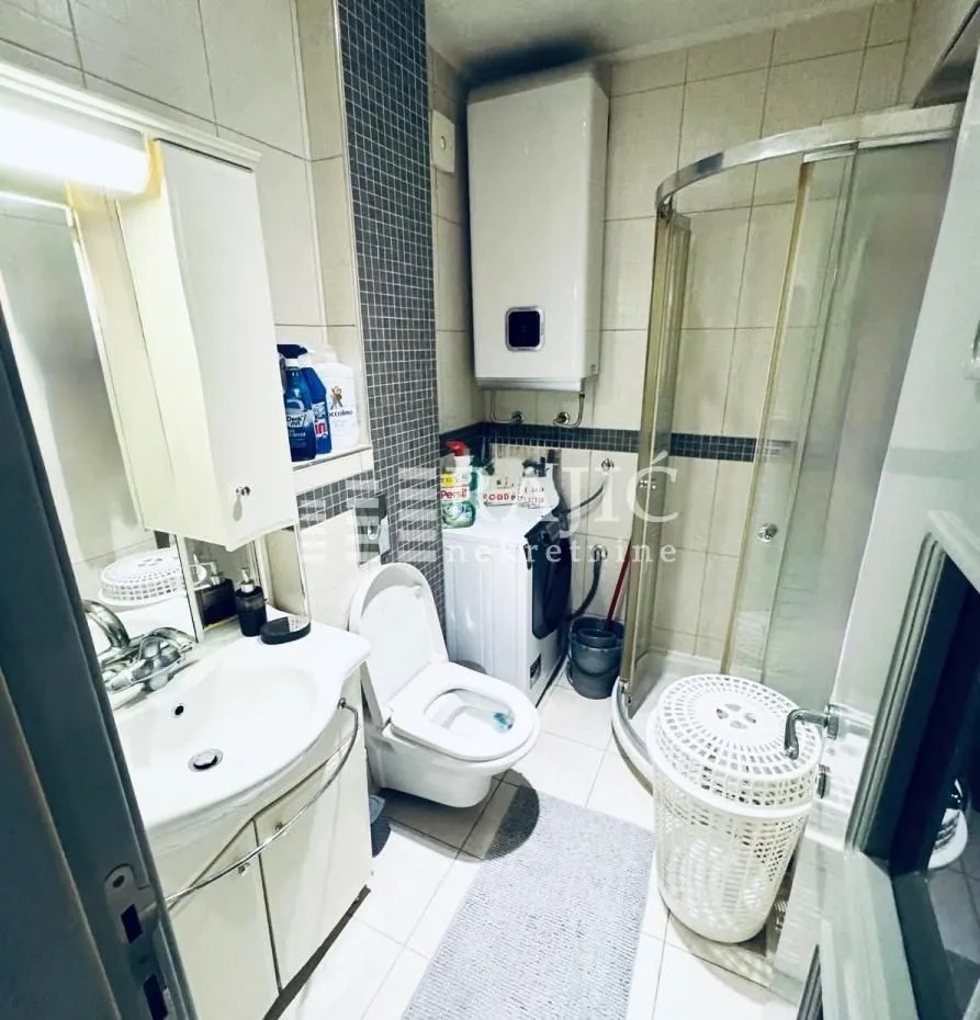 Small bathroom with a shower cabin, sink, and washing machine.