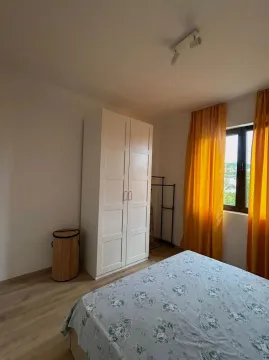Spavaća soba sa krevetom, bijelim garderoberom i prozorom sa žutim zavjesama. - image 7