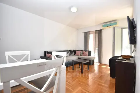 Living room with a sectional sofa, dining table, and parquet flooring. - image 2