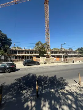View of the building construction site with a crane from the street. - image 2