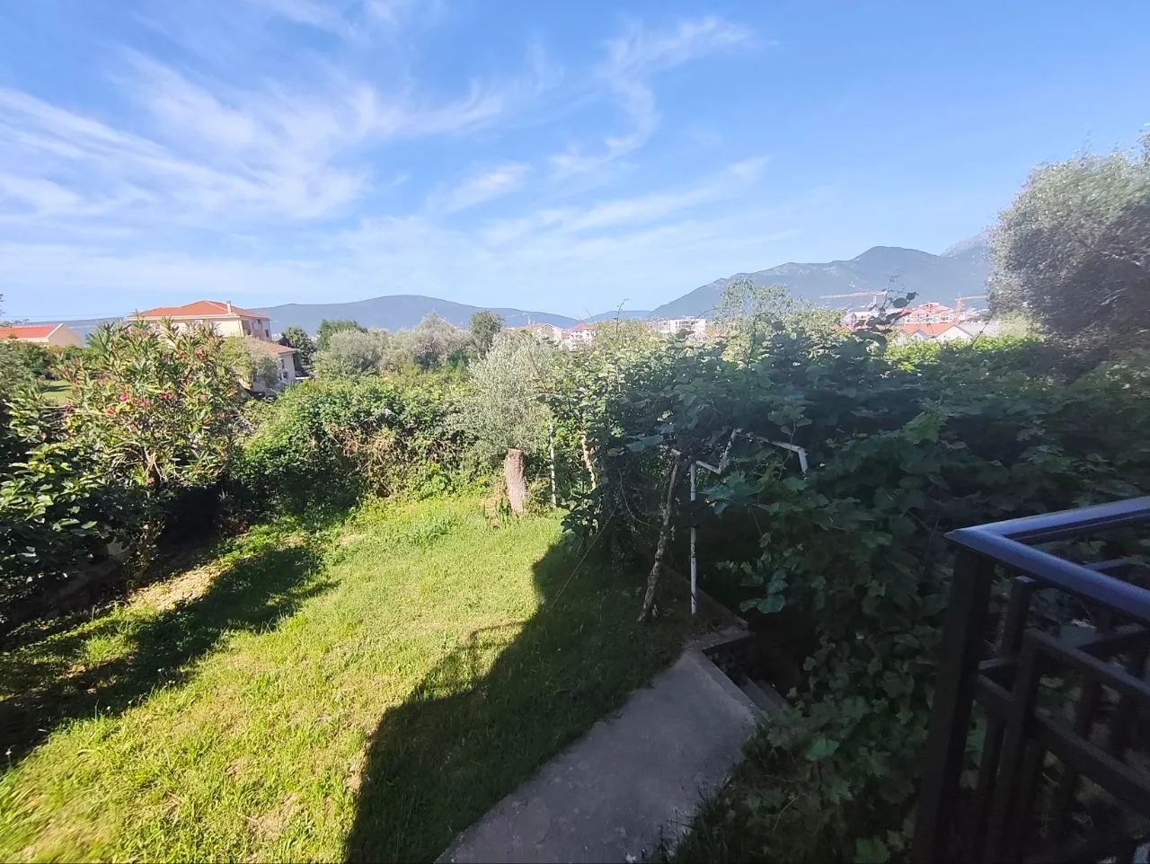 Pogled iz dvorišta na okolno zelenilo i planine.