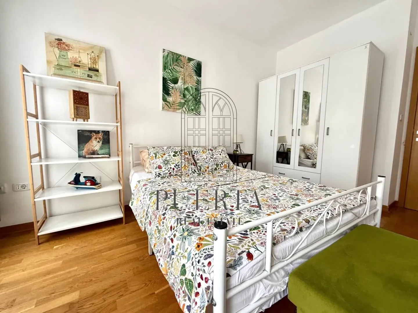 Furnished bedroom with a double bed, white wardrobe, and shelving unit.