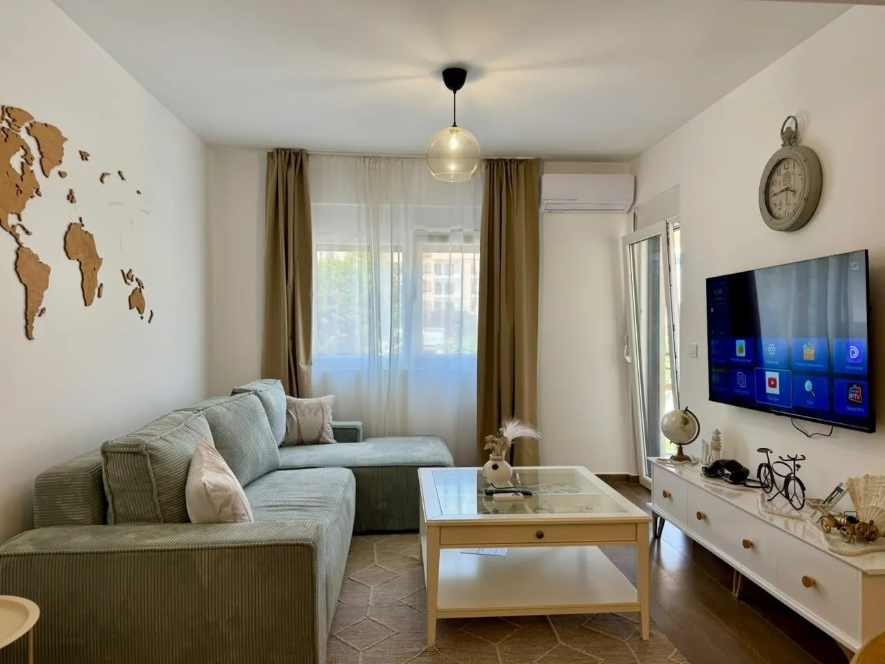 Bright living room with a sectional sofa, TV, and wooden wall decoration.