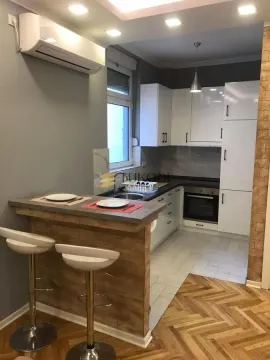 Modern kitchen with a breakfast bar and built-in appliances. - image 10