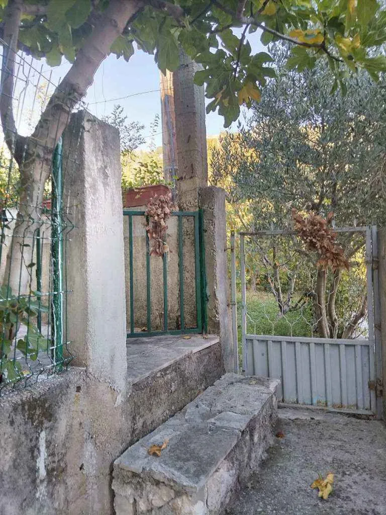 Ulaz u dvorište sa metalnom kapijom i kamenim stepenicama.