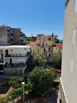 View from the terrace of surrounding buildings, greenery, and the sea in the distance. - image 3