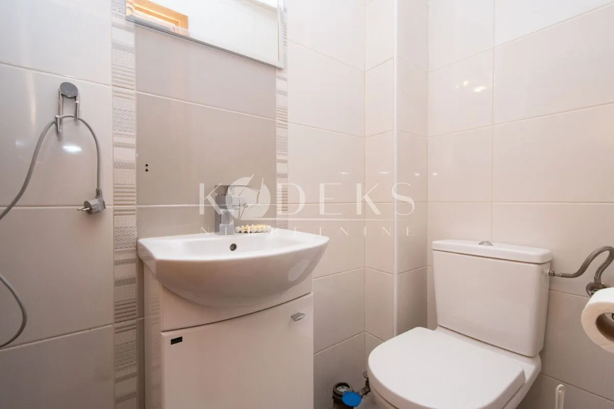 Manje kupatilo sa umivaonikom i wc šoljom obloženo svijetlim pločicama.