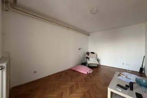 Prazna soba sa parketom na podu i vidljivim instalacijama na zidu. - image 5