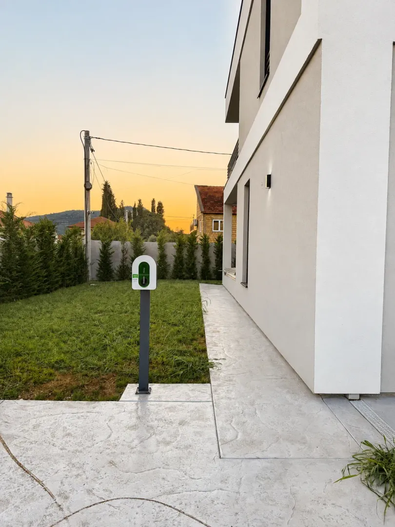House yard with lawn, walkway, and an electric car charger.